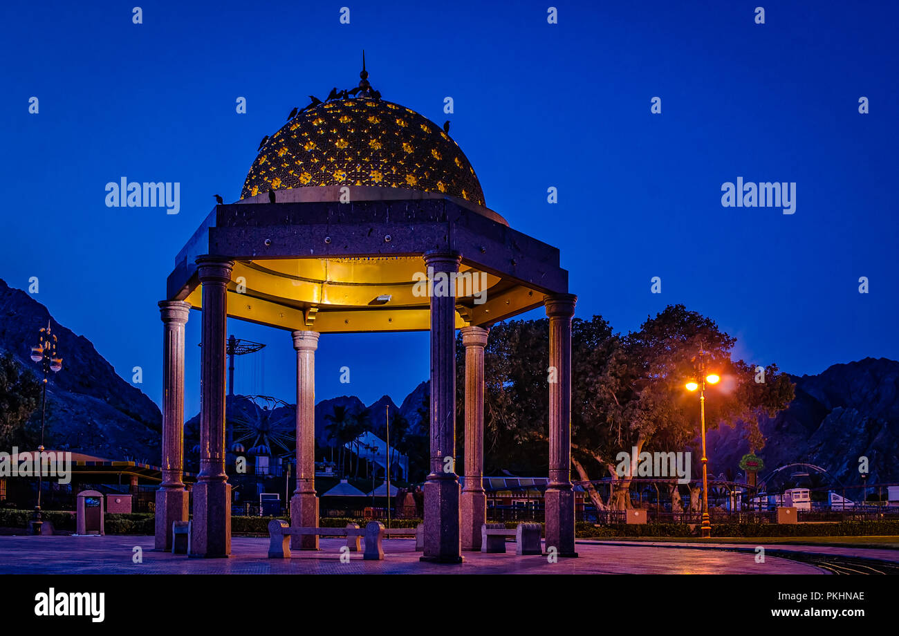 Gazebo dome baignée de lumière jaune. Une atmosphère romantique au cours de l'heure bleue, Muscat, Oman. Banque D'Images