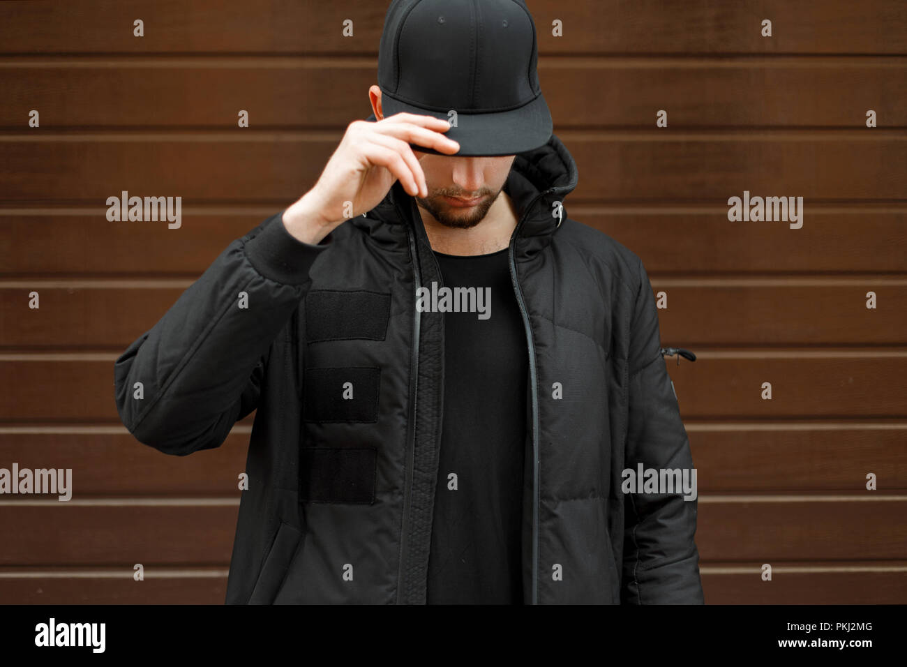 Jeune homme dans une casquette de baseball à la mode noir et une veste  chaude d'hiver posant dans la rue Photo Stock - Alamy