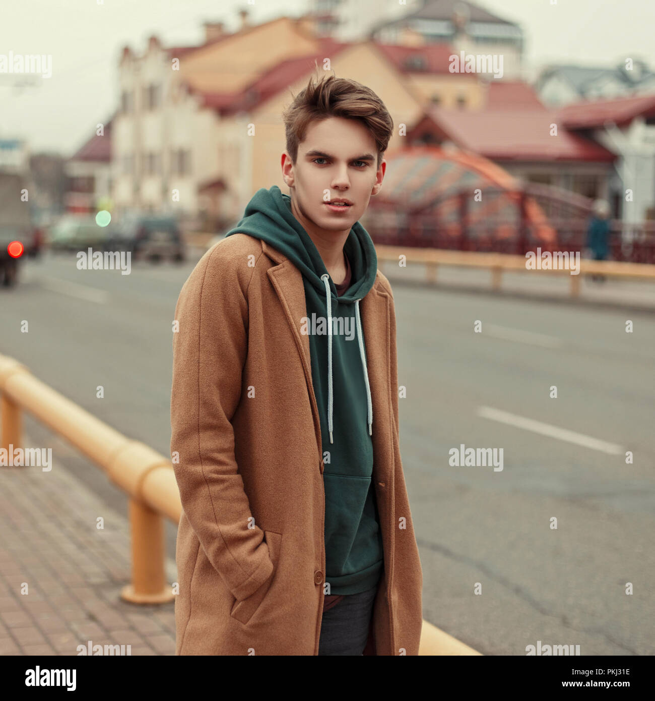 Beau jeune homme élégant dans un manteau rétro avec hoodie sur rue Photo  Stock - Alamy