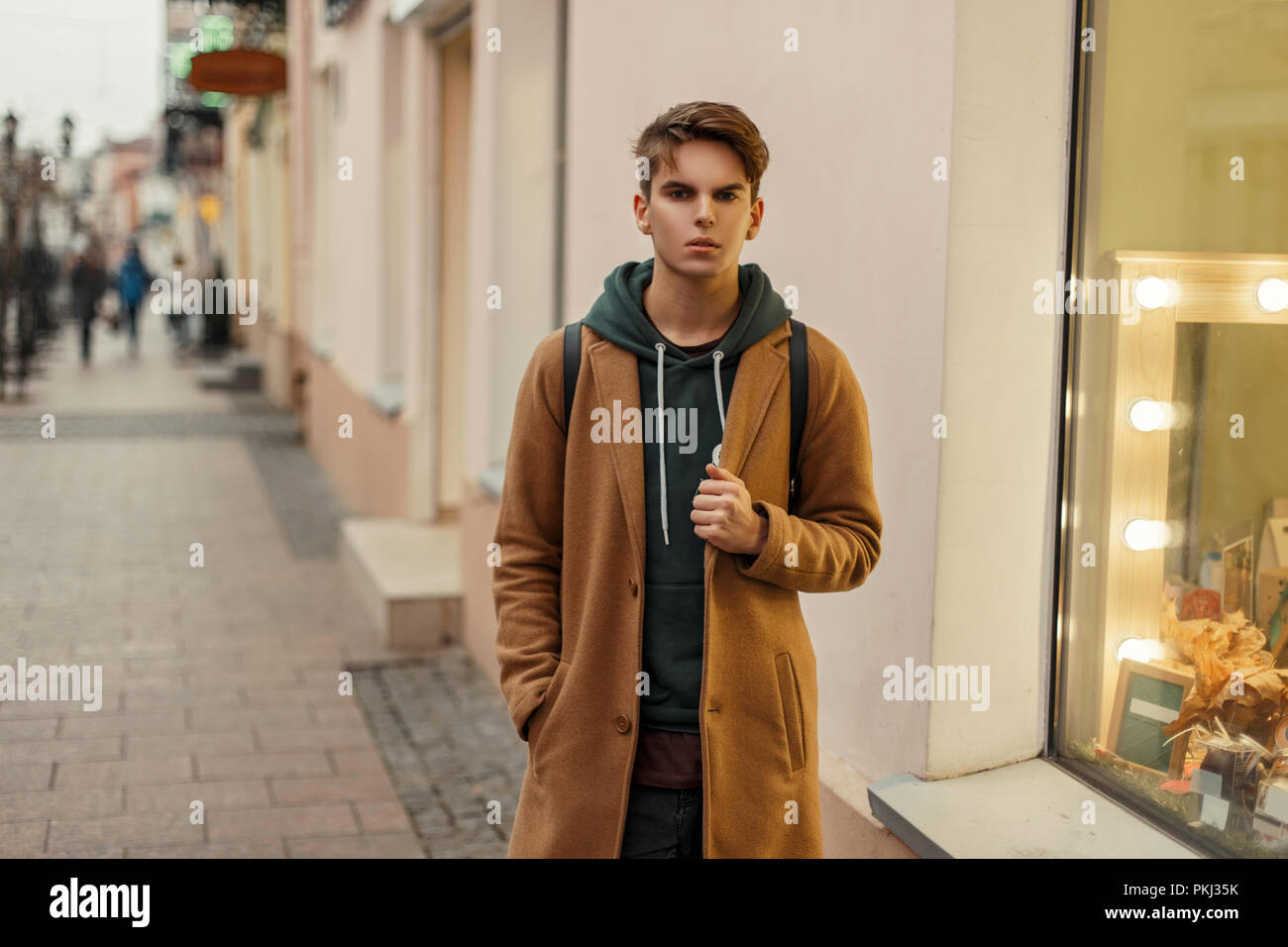 Bel homme élégant dans un quartier branché de manteau avec capuche à la  mode dans la rue Photo Stock - Alamy