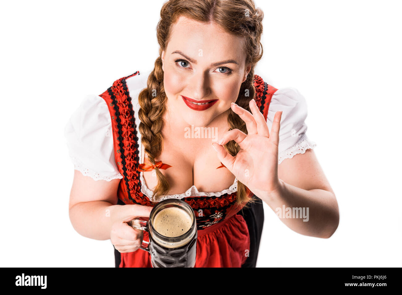 Portrait de serveuse Oktoberfest bavarois traditionnel en dress holding mug de bière brune et montrant ok sign isolé sur fond blanc Banque D'Images