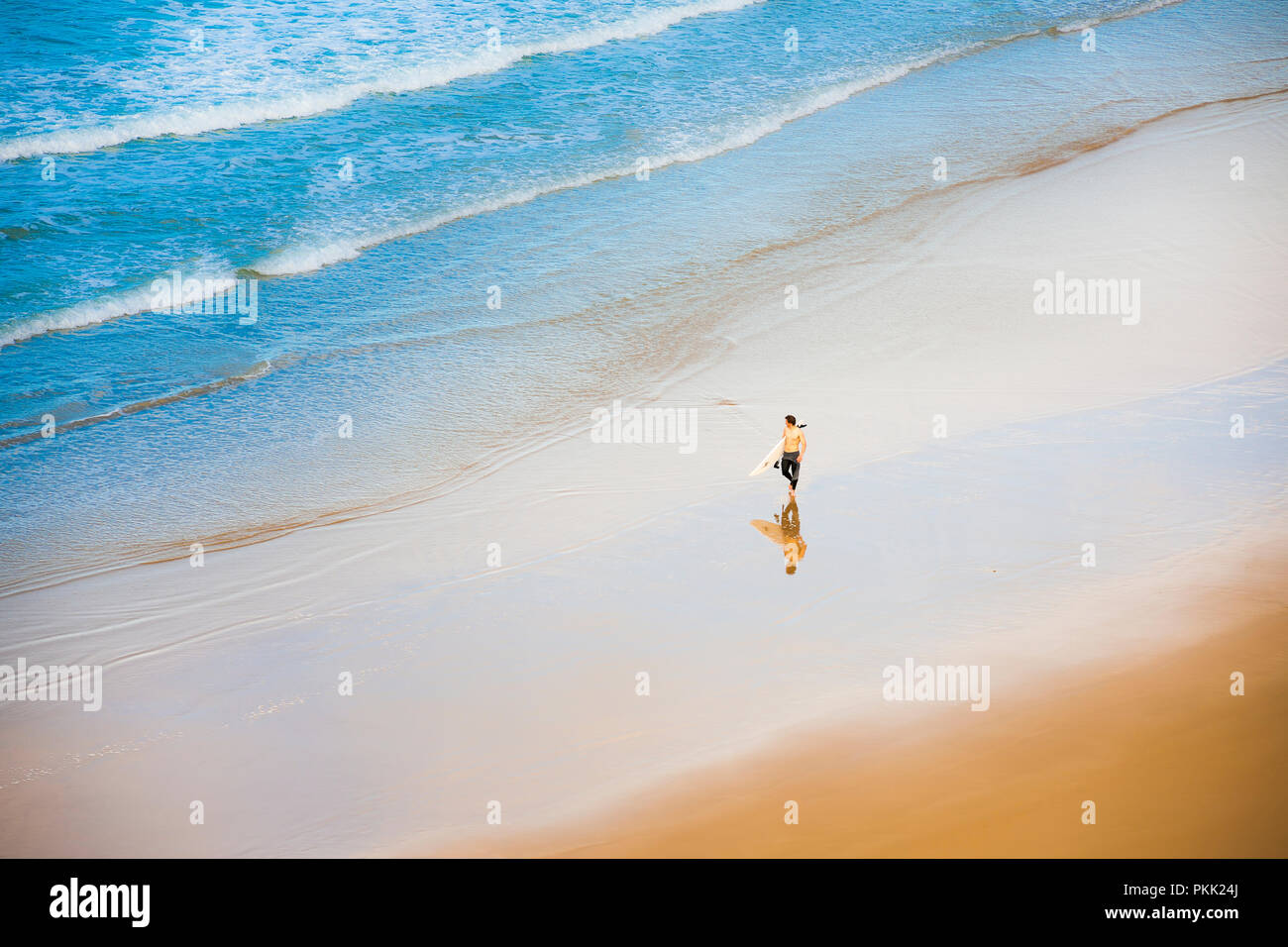 Surfeur transportant des planches de surf sur une plage de sable, vue d'en haut Banque D'Images