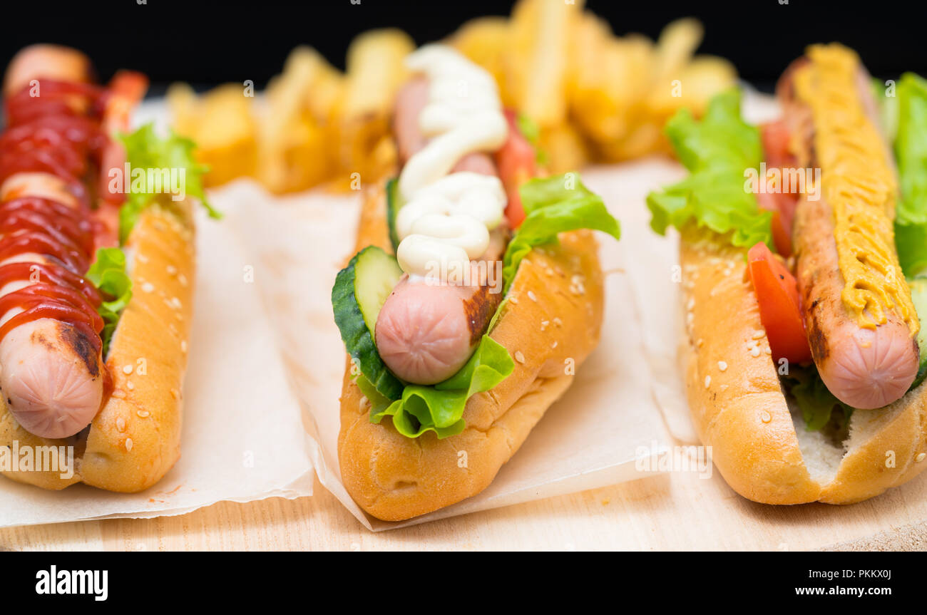 Trois chiens chauds assortis avec les saucisses de Francfort en tête avec des pansements différents à savoir la mayonnaise, ketchup et moutarde Banque D'Images