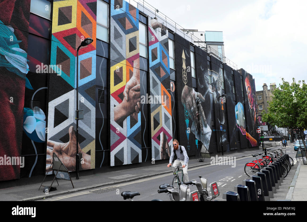 Un vélo branché sur un vélo passé une grande peinture murale art de rue à New Inn Yard Shoreditch près de Hackney dans l'Est de Londres UK KATHY DEWITT Banque D'Images