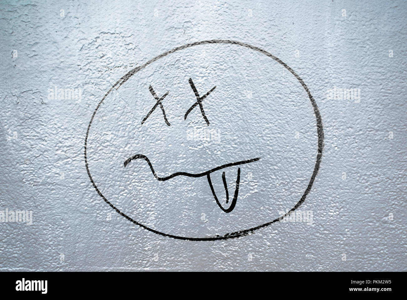 Graffiti de visage drôle dessiné à la main avec les yeux croisés et la langue sur un mur au bord de la rivière à Bratislava, Slovaquie Banque D'Images