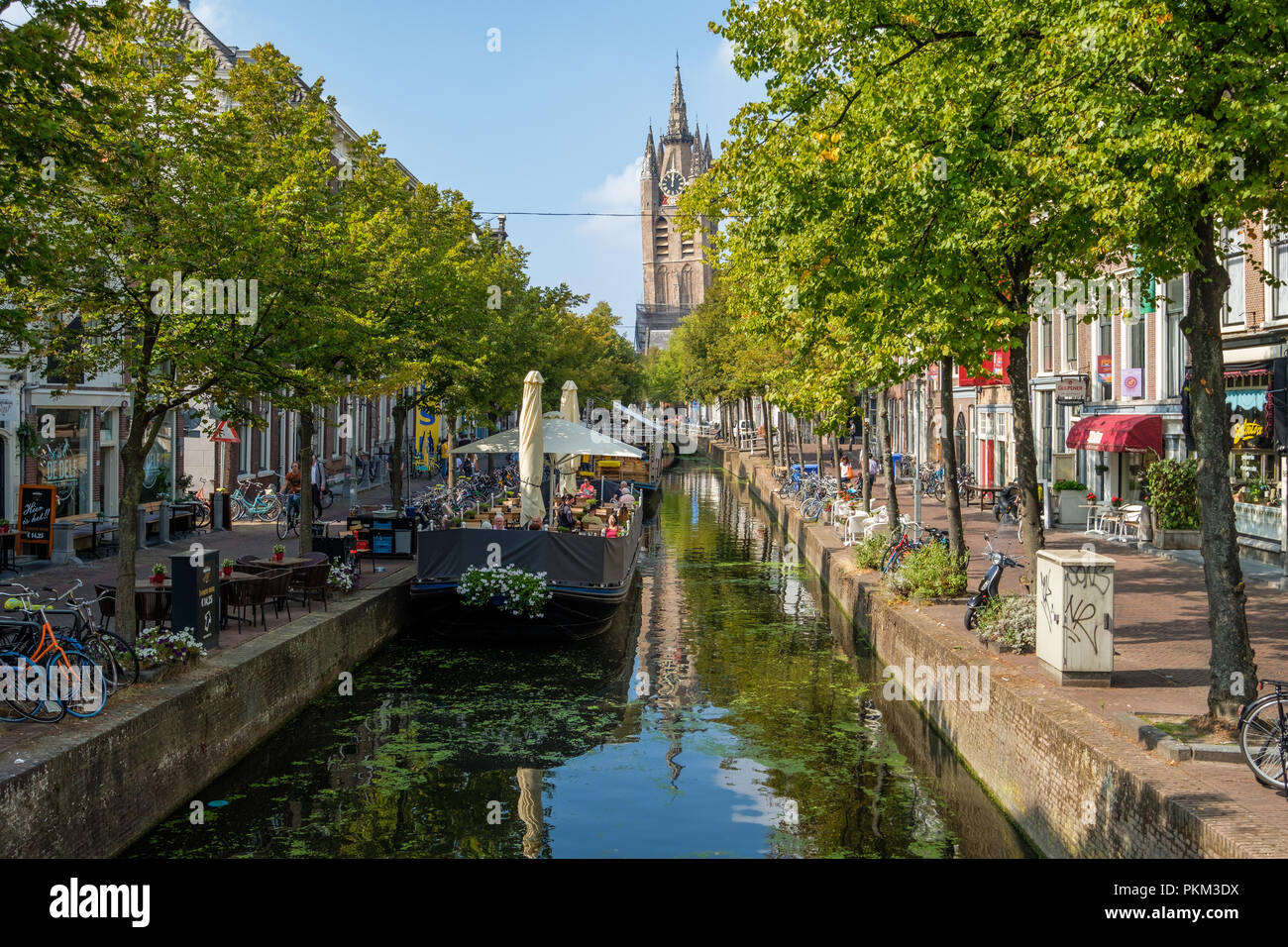 Une terrasse bateau dans un canal historique avec vue sur la tour penchée de la Oude Kerk à Delft. Banque D'Images