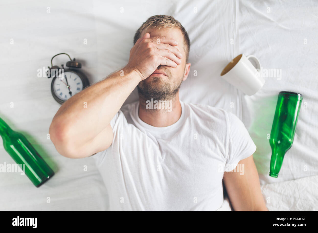 Jeune homme séduisant au lit le matin après nuit boire Banque D'Images