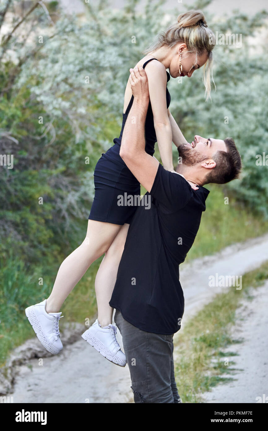 L'Est de la mode, un couple amoureux serrant contre l'arrière-plan des  buissons et de la route. L'homme et de la femme relation amoureuse. Homme  tenant une femme Photo Stock - Alamy