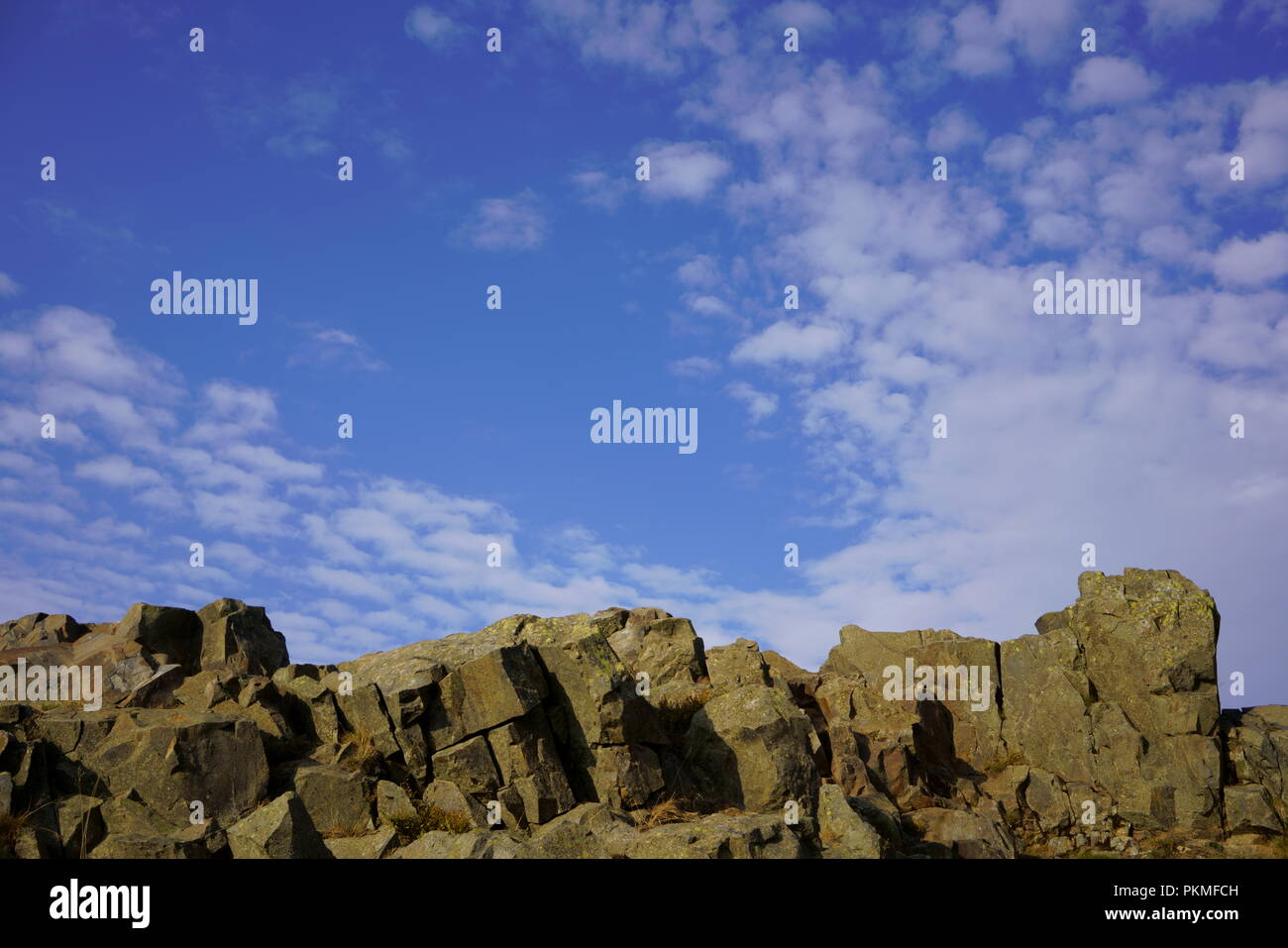 Les rochers de granit ensoleillé partiellement nuageux contre un fond de ciel bleu. L'espace de copie pour un texte et design. Banque D'Images