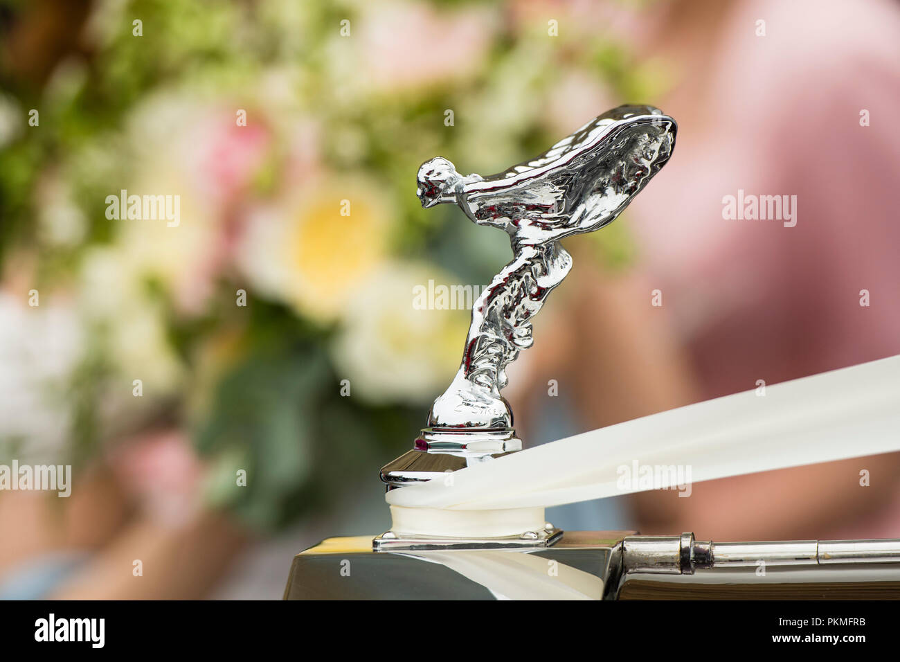 Mariages au Royaume-Uni - Détail de la Rolls Royce "l'esprit de l'extase' sur l'ornement de capot de voiture de noce, du flou de l'arrière-plan des fleurs de mariage bouquet de mariée Banque D'Images