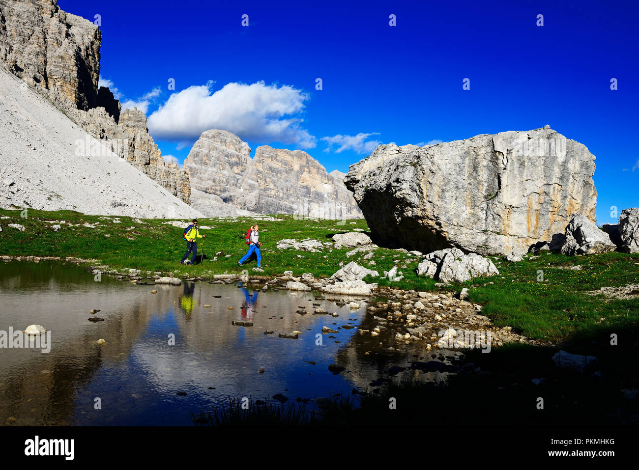 Les randonneurs en dessous de la selle Patern se reflètent dans une flaque d'eau, sentier 101, derrière le sommet de l'Einser, Dolomites de Sexten Banque D'Images