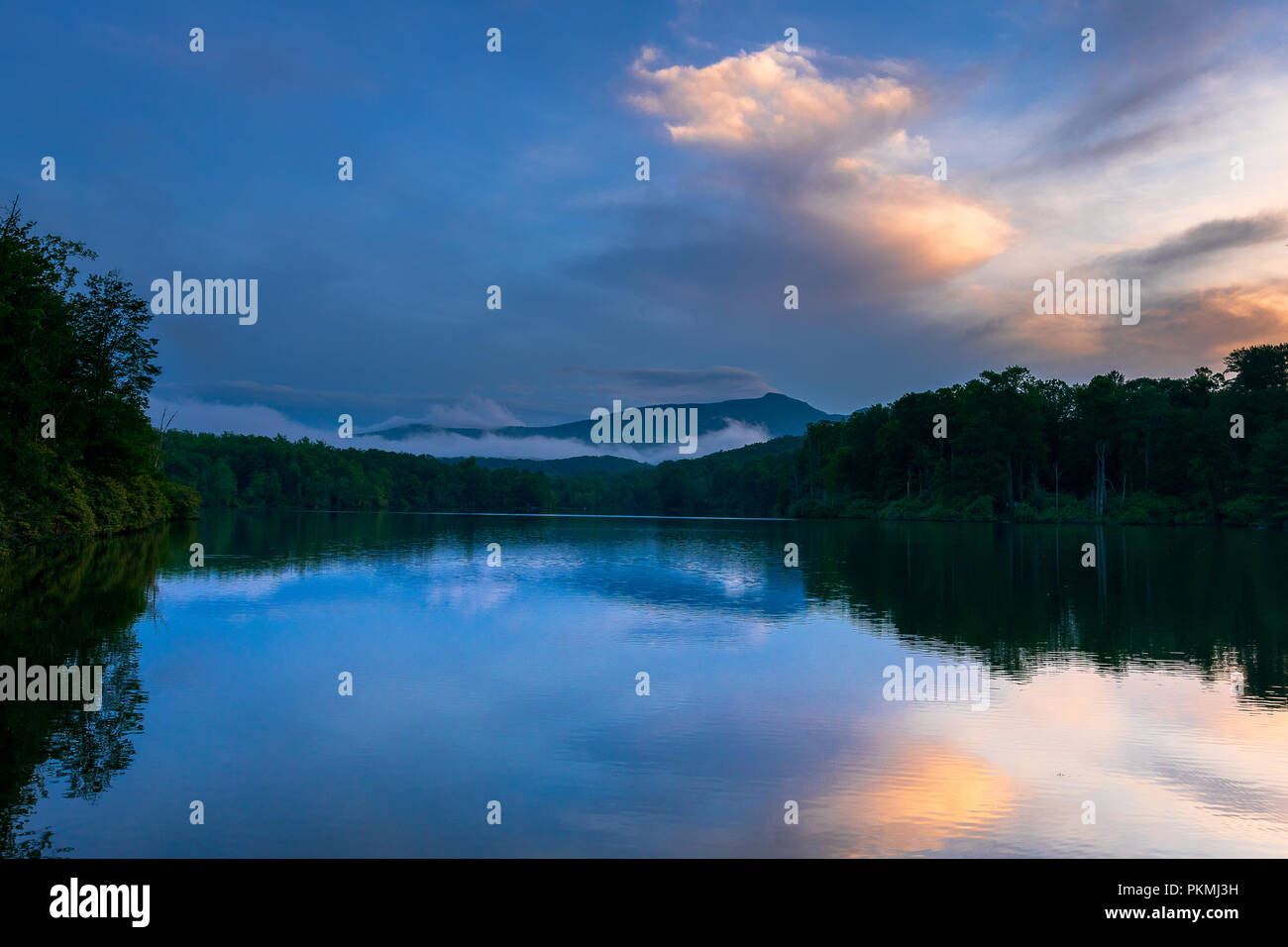 Foggy Grandfather Mountain reflète dans : le lac de la Caroline du Nord. Tout comme le soleil se couche les nuages s'illuminèrent et se reflètent dans le lac de prix. Banque D'Images