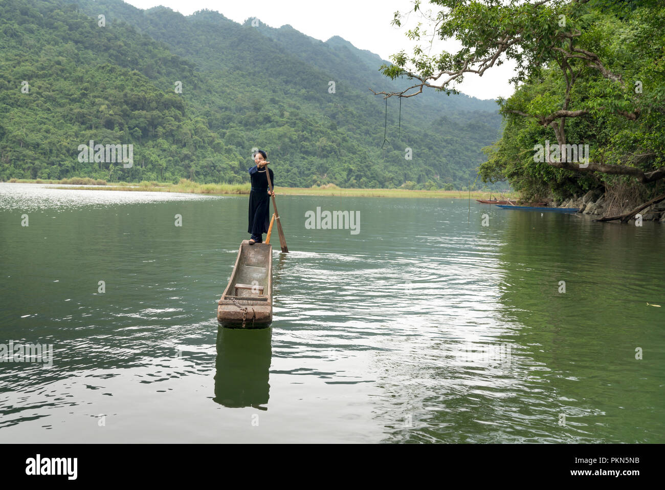 Une femme de la minorité ethnique Tay, dans son costume traditionnel est l'aviron une pirogue sur le lac Ba Be. Lac de Ba Be est un célèbre lieu touristique dans la région de Bac Kan, VN Banque D'Images