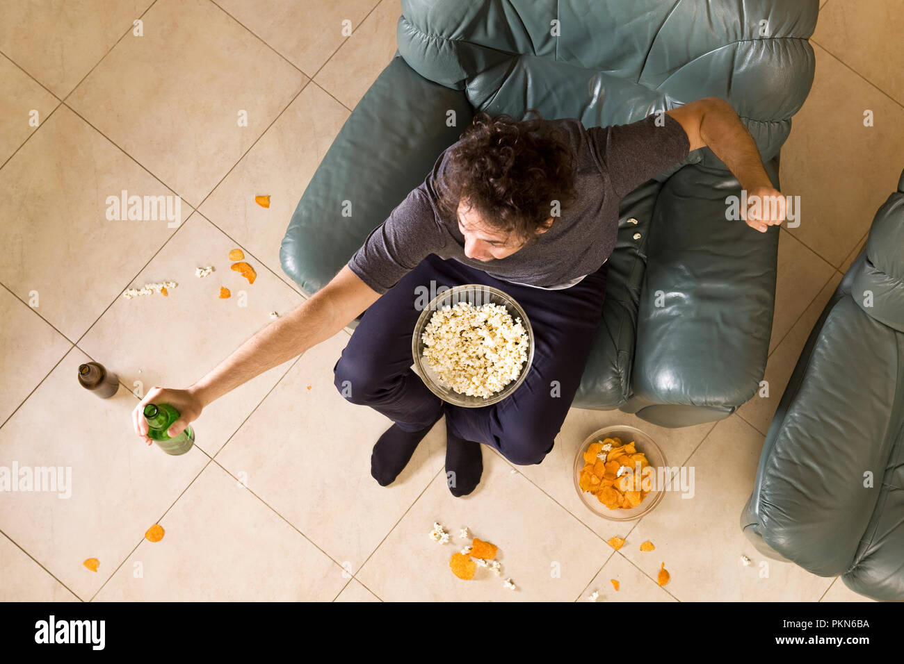 Vue du dessus de l'heureux jeune homme avec bière et chips sur le canapé Banque D'Images