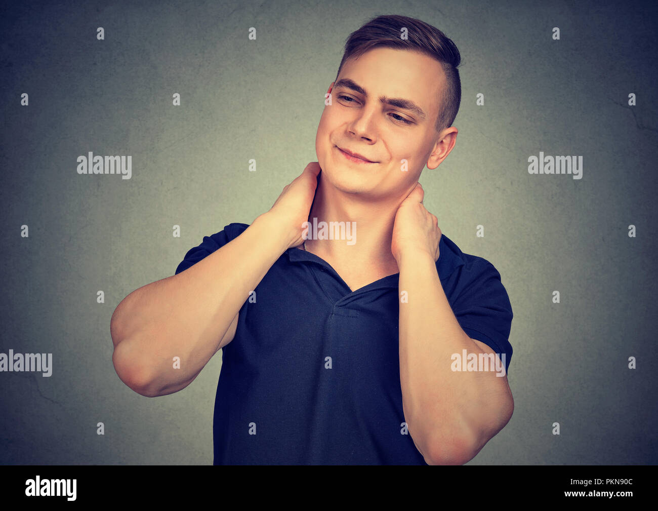 Jeune homme à la fatigue et se frottant le cou ayant la douleur et à l'écart en froncement sur fond gris Banque D'Images