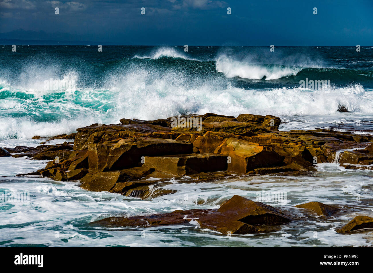Moyennes vagues se brisant sur les roches brunes dans l'Atlantique Sud, Afrique du Sud Banque D'Images