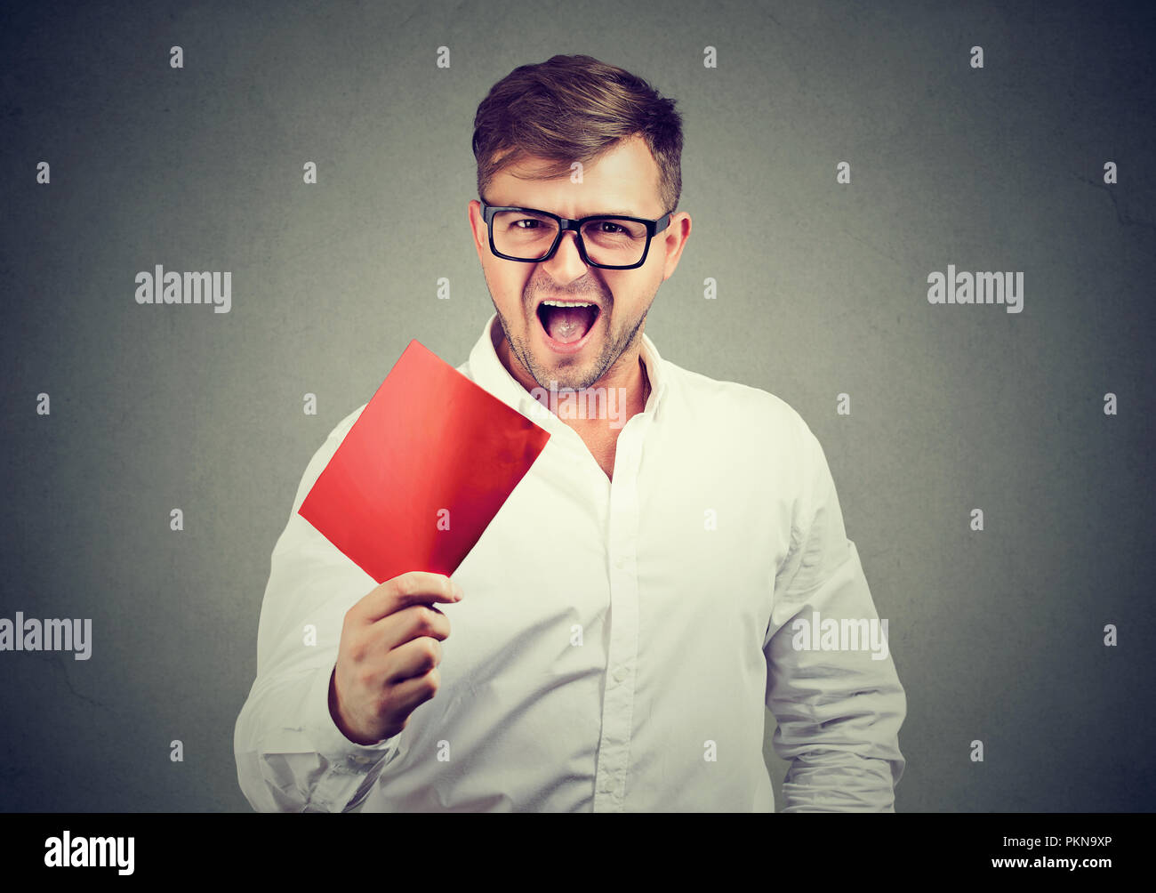 Angry Young man lunettes hurlant de frustration et montrant une carte de mort rouge. Banque D'Images