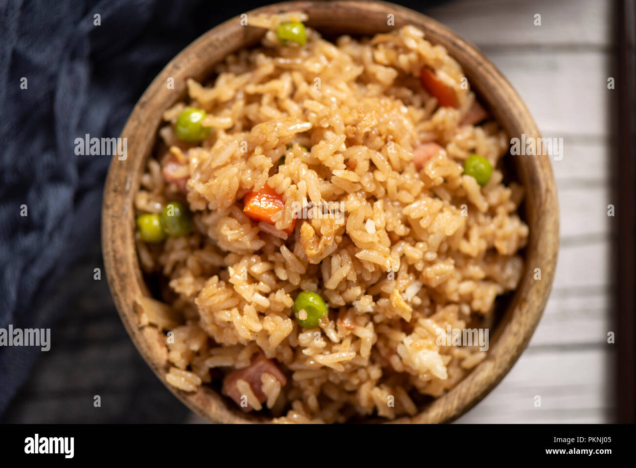 Portrait d'un bol de buis avec un riz frit à la chinoise et une paire de baguettes sur une table en bois blanc rustique Banque D'Images