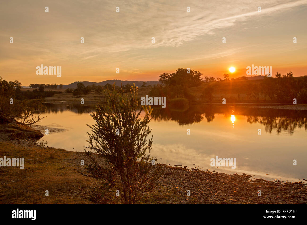 Ciel orange vif avec sun rising over et se reflètent dans les eaux calmes de la rivière Clarence à l'aube à Lilydale en NSW Australie Banque D'Images
