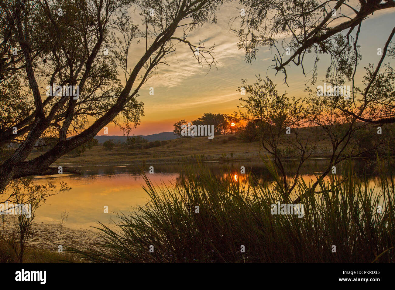Orange ciel coloré avec sun rising over et se reflètent dans les eaux calmes de la rivière Clarence à l'aube à Lilydale en NSW Australie Banque D'Images