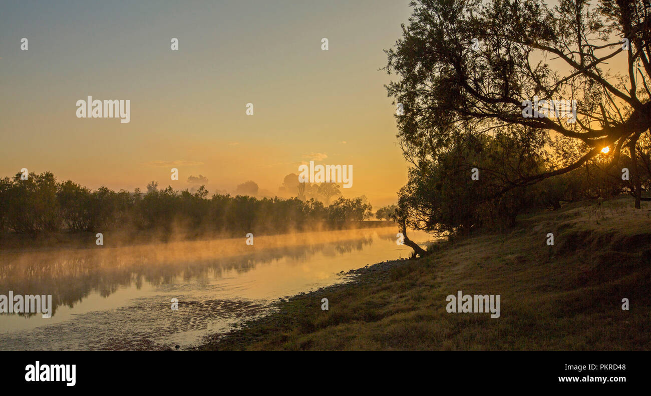 Vue panoramique de ciel orange et de la brume qui s'élève au-dessus des eaux calmes de la rivière Clarence au lever du soleil à Lilydale en NSW Australie Banque D'Images