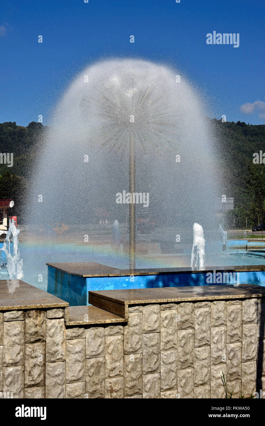 Une fontaine sphérique injecteur dans un pool de pulvérisation crée un rideau d'eau d'une merveilleuse enveloppe paraboloïde en raison de la gravité, avec un léger Rainbow Banque D'Images