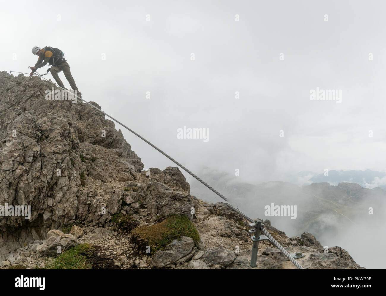 Young attractive male d'alpiniste sur une pente raide et exposé Via Ferrata en Alta Badia dans le Tyrol du Sud dans les Dolomites italiennes Banque D'Images