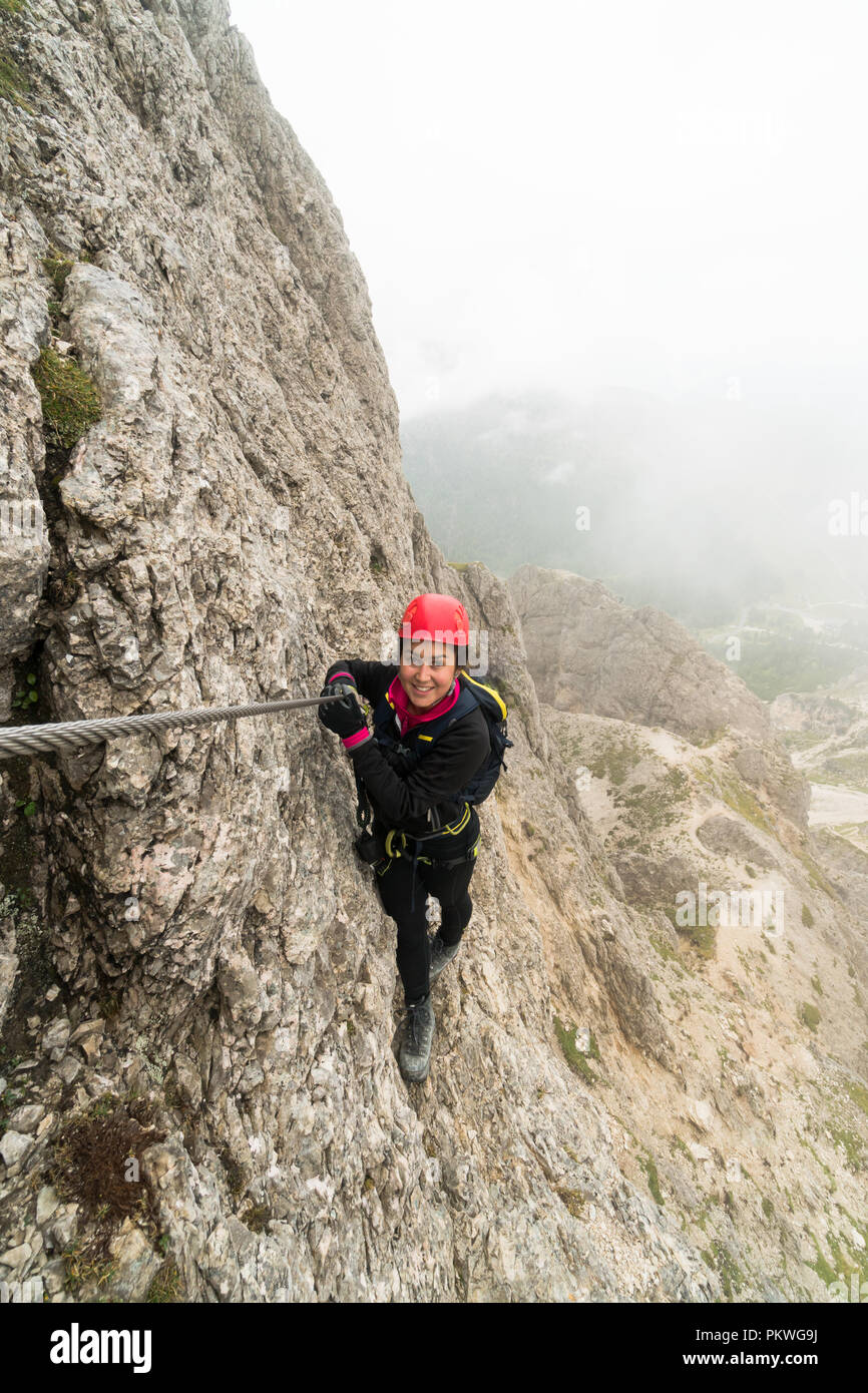 Les jeunes femmes attrayantes d'alpiniste sur une pente raide et exposé Via Ferrata en Alta Badia dans le Tyrol du Sud dans les Dolomites italiennes Banque D'Images