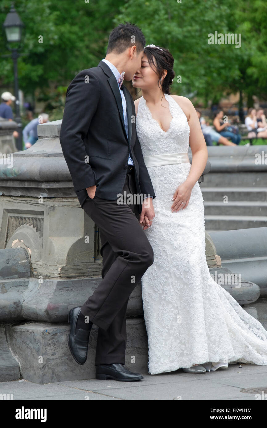 Un couple américain asiatique posent pour des photos près de la fontaine à Washington Square Park à Manhattan, New York City. Banque D'Images