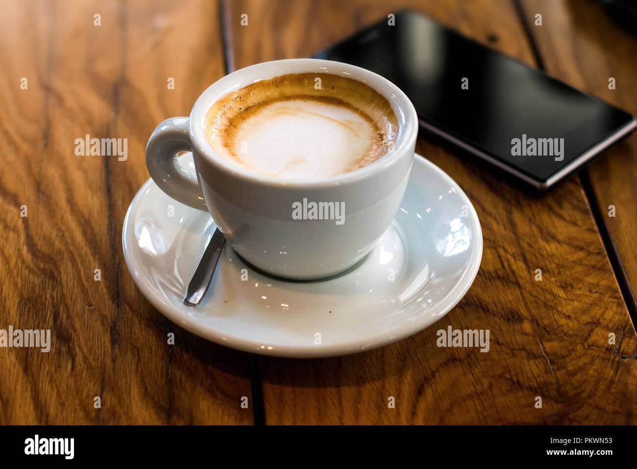 Une tasse de café et smart phone sur une table à café woden Banque D'Images