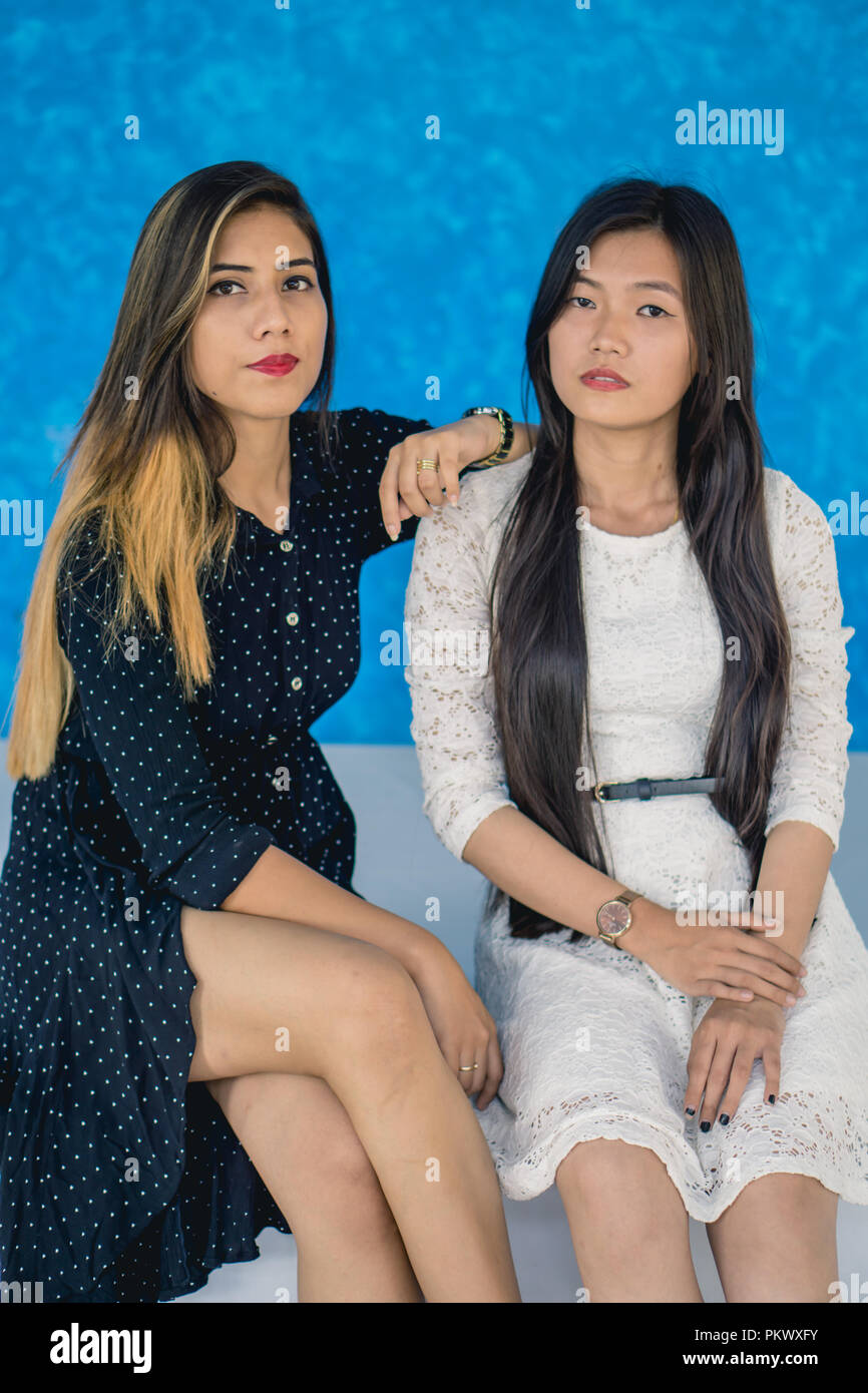 Deux jeune fille posant pour l'appareil photo sur un fond bleu. Banque D'Images