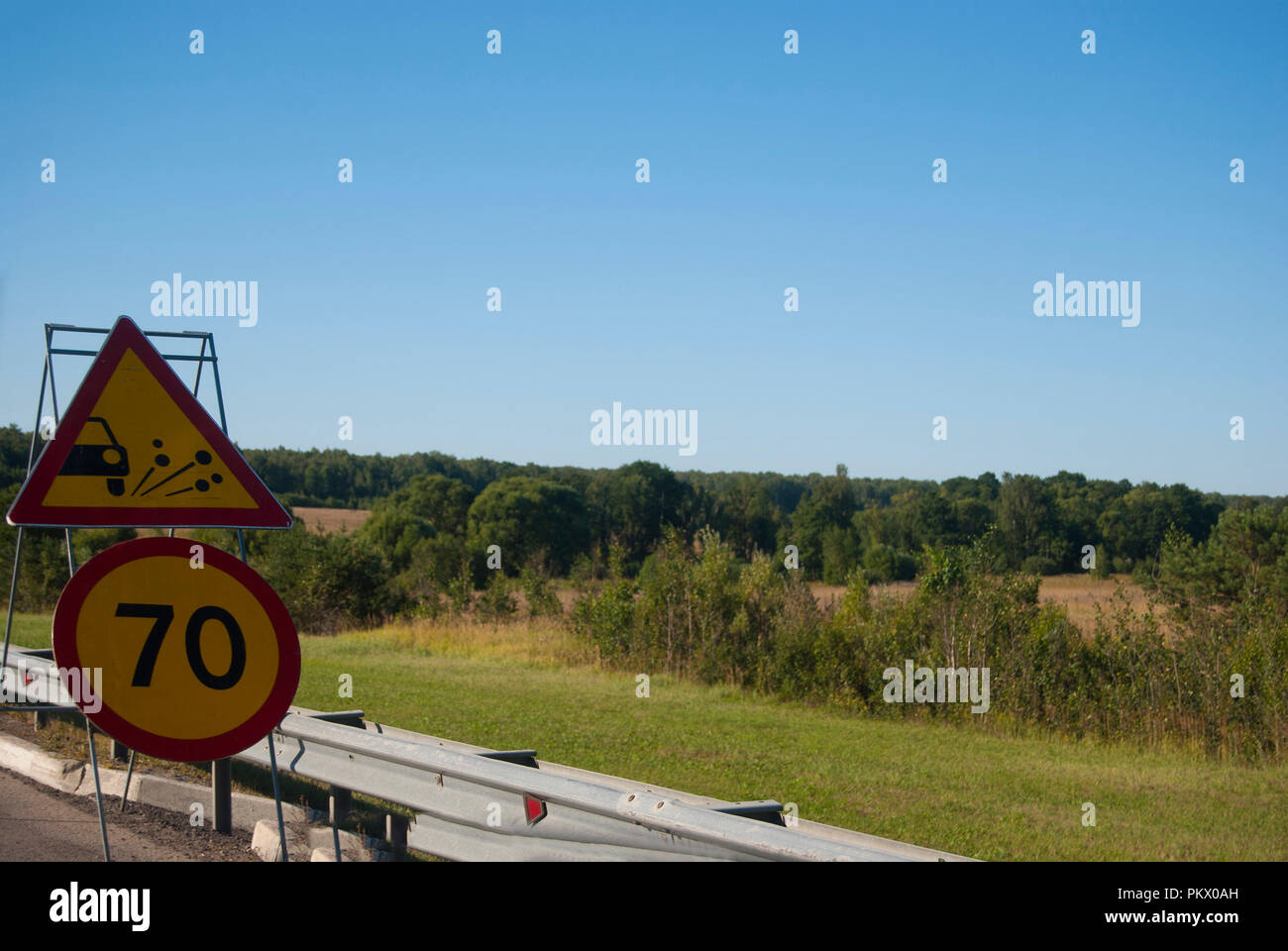 Deux panneaux routiers : une limite de vitesse de jusqu'à 70 et d'une éjection de gravier. La réparation des routes. Banque D'Images