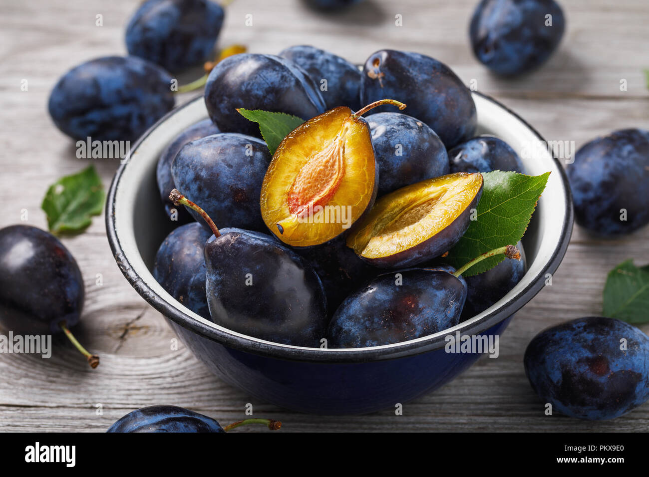 Bol plein de pruneaux mûrs fruits sur une table en bois, gros plan Banque D'Images