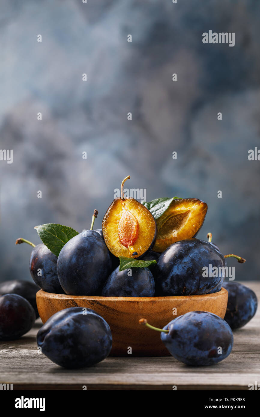 Plaque complète de pruneaux mûrs fruits sur une table en bois avec un espace réservé au texte Banque D'Images