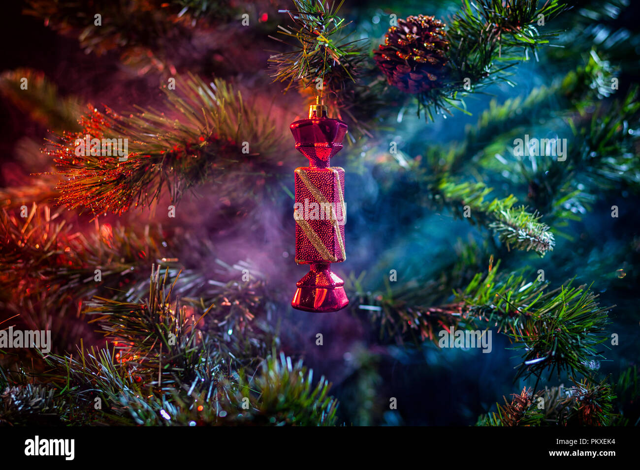 La décoration des boules de Noël rouge brillant avec des bonbons dans la chambre de fumée de couleur violet-rouge, sur un fond d'arbres de Noël. Concept d'une voiture de Noël moderne Banque D'Images