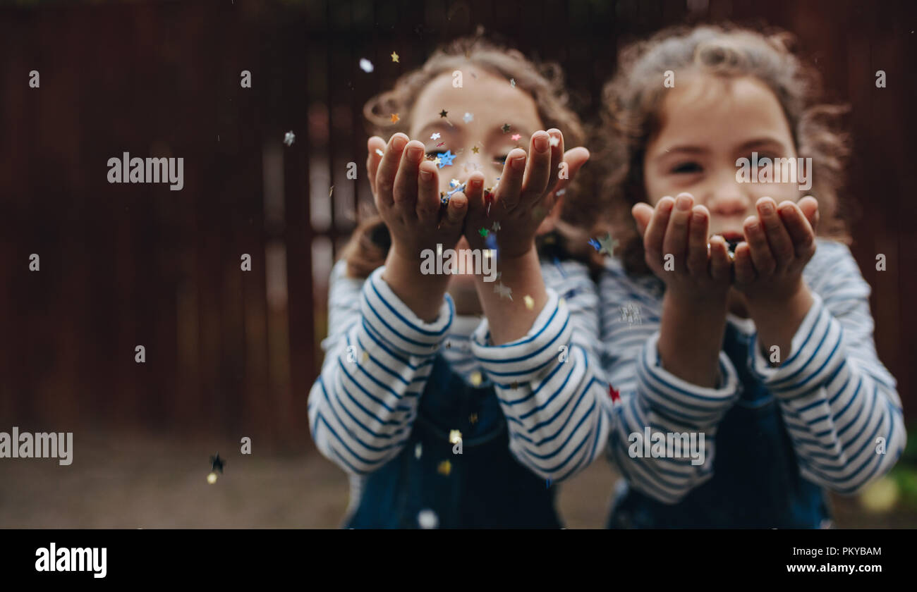 Les jeunes filles de la neige à confettis. Deux sœurs s'amusant et de la neige à confettis à l'extérieur. Banque D'Images