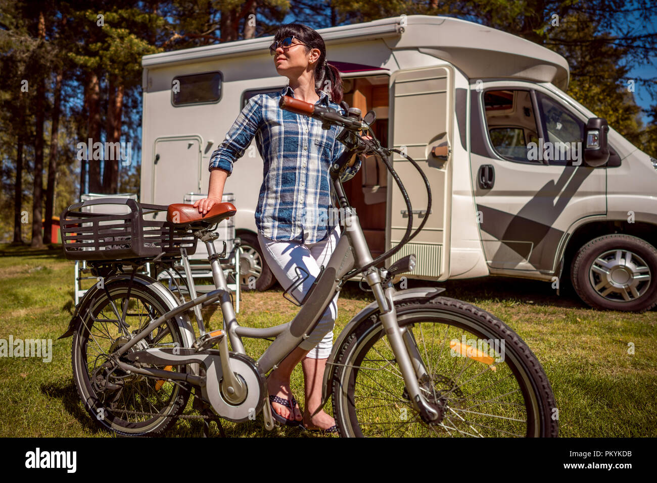 Femme sur vélo électrique reposant sur le camping. Vacances famille vacances, voyages voyage en camping-car, caravane locations de voiture VR. Banque D'Images