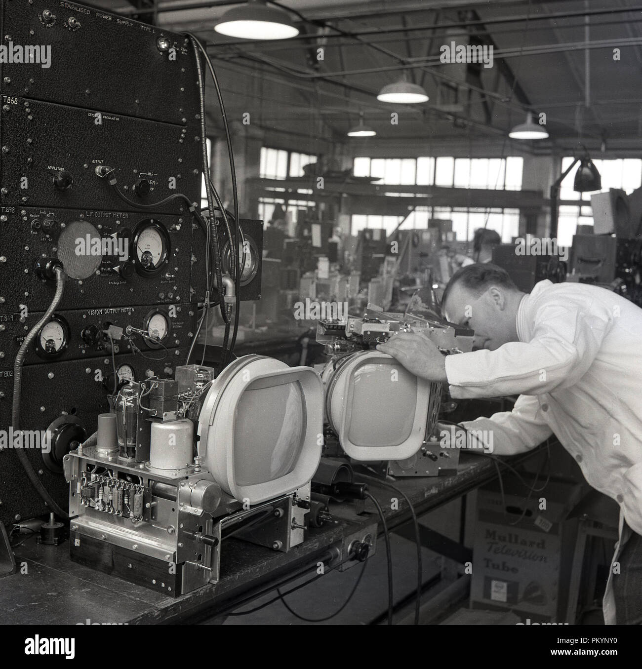 Années 1950, historique, les hommes en blouse blanche technicien travaillant sur les composants d'appareils de télévision à l'usine de Radio Bush, un des leaders de l'électronique grand public britannique en cette ère de l'entreprise. Banque D'Images