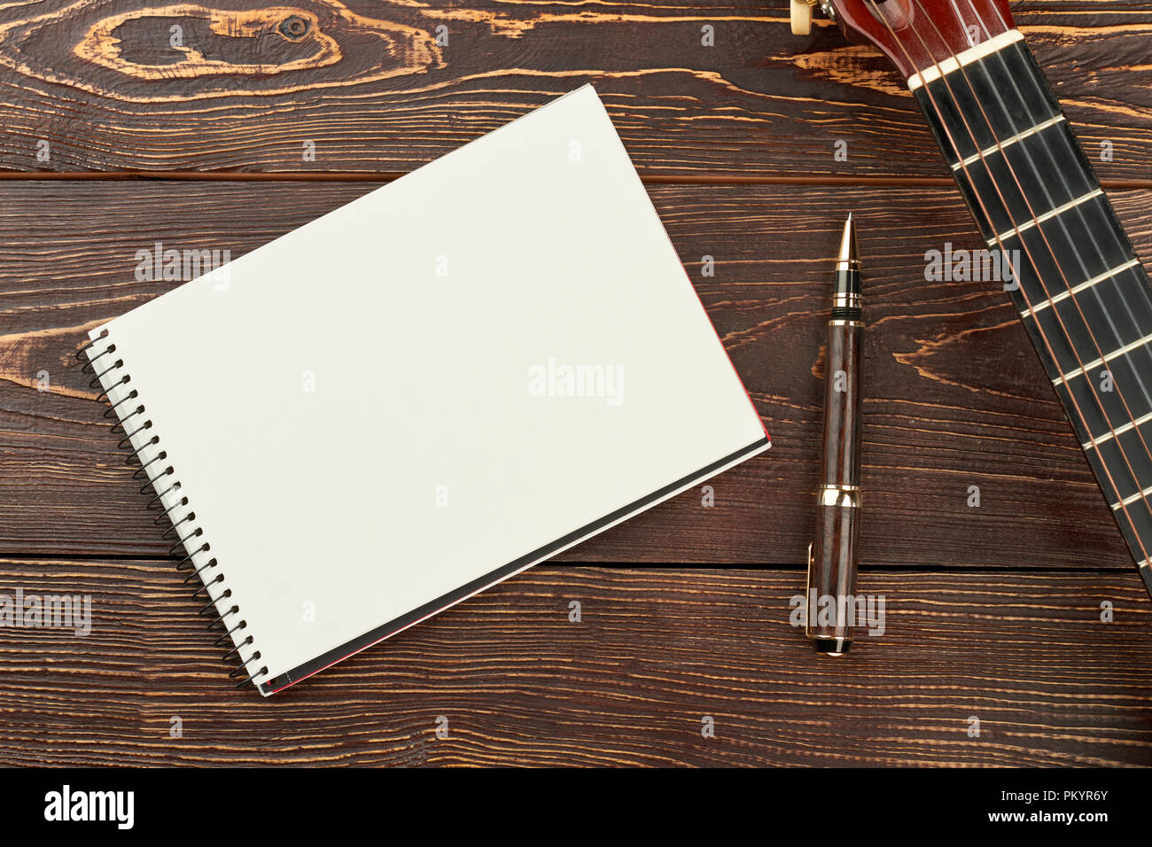 Ordinateur portable blanc, stylo et guitare. Fond en bois brun avec copie papier de l'espace livre, guitare et stylo. Musicien concept d'espaces de travail. Banque D'Images