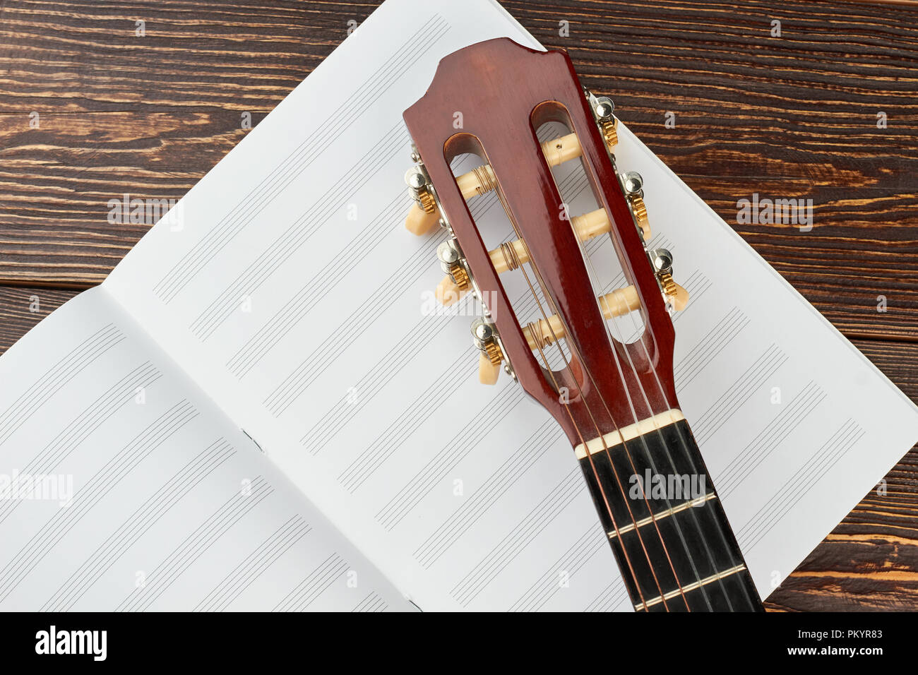 Tête de guitare sur des notes de musique. Chevilles et de la tête d'une guitare sur notes de musique livre. Music scores sur fond de bois. Banque D'Images