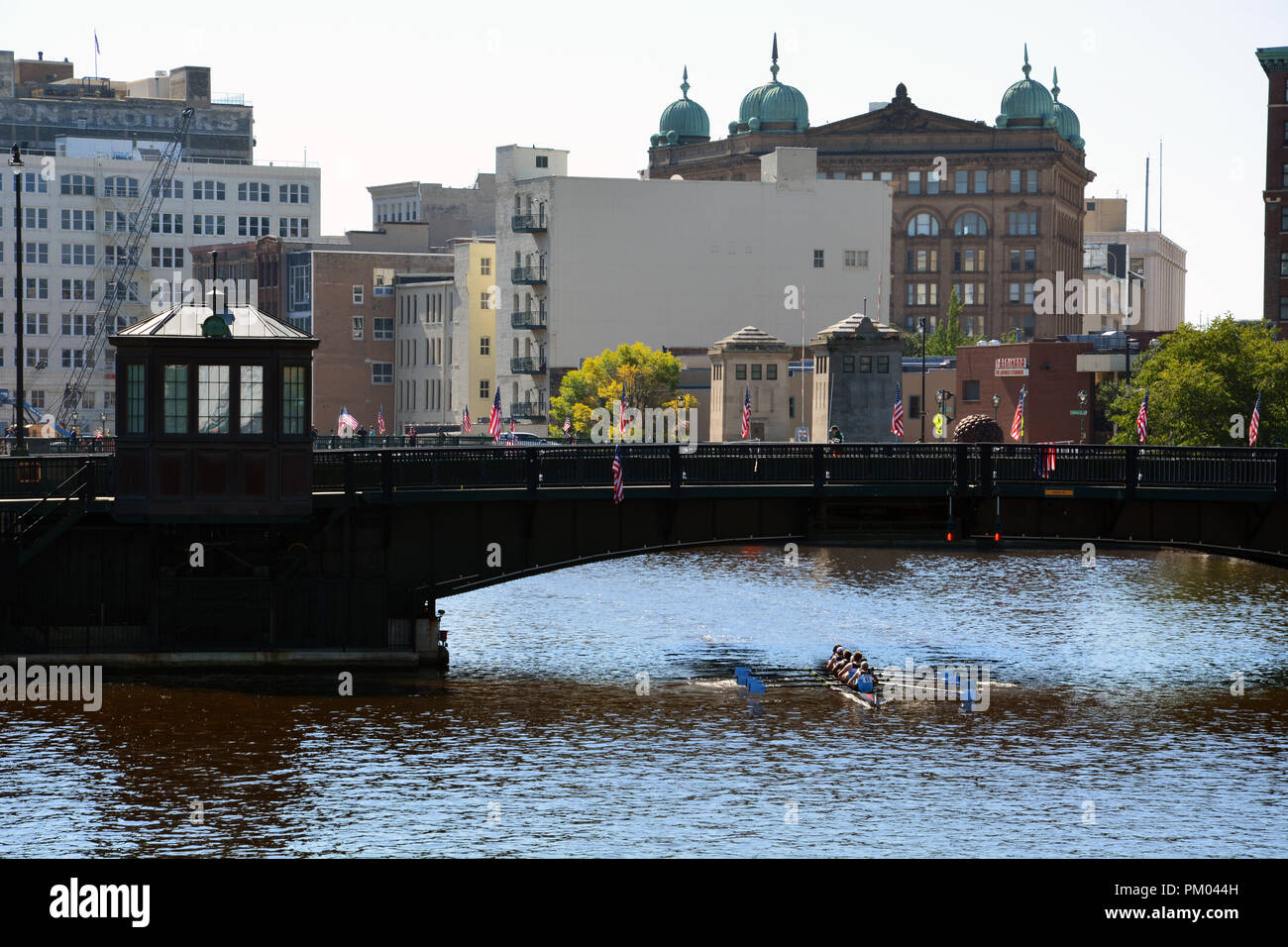 Une équipe d'aviron passe sous le pont de la rue de l'État sur la rivière Milwaukee. Banque D'Images