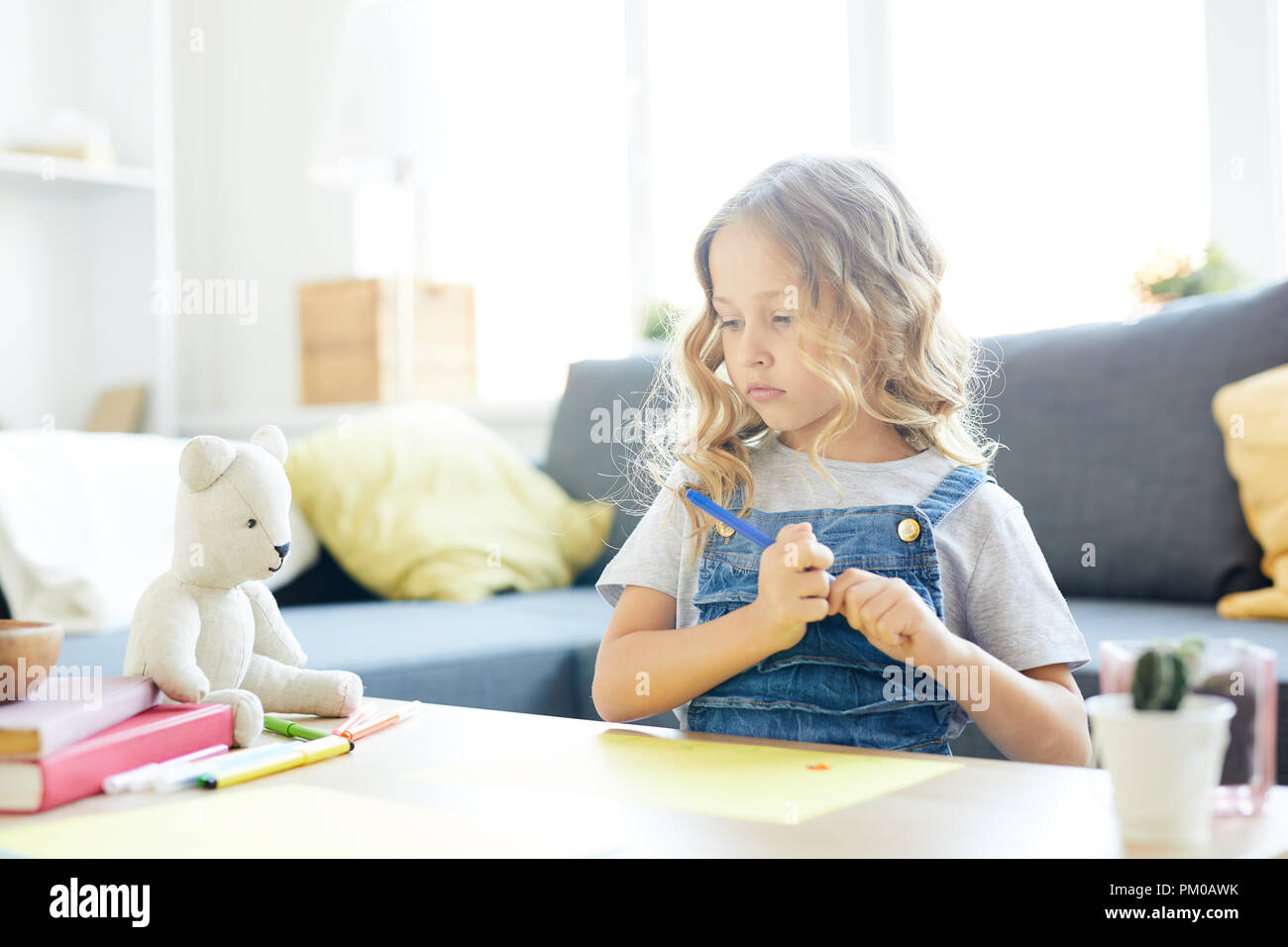 Jolie fille aux cheveux blonds frisés idée de penser avant de dessiner avec des crayons de couleur Banque D'Images