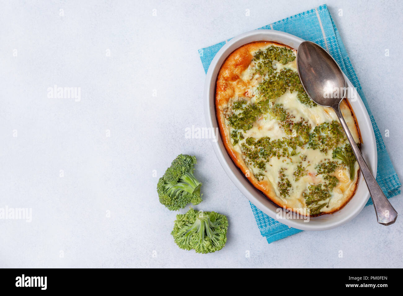 Petit déjeuner sain. Les brocolis, fromage, oeufs cocotte dans un bol pour la cuisson sur un fond de béton gris. Vue de dessus Banque D'Images