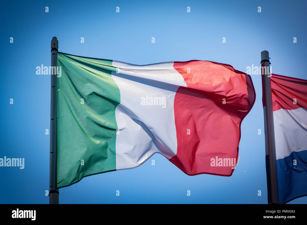 Drapeau Italien voletant dans le vent, avec ciel bleu. Banque D'Images