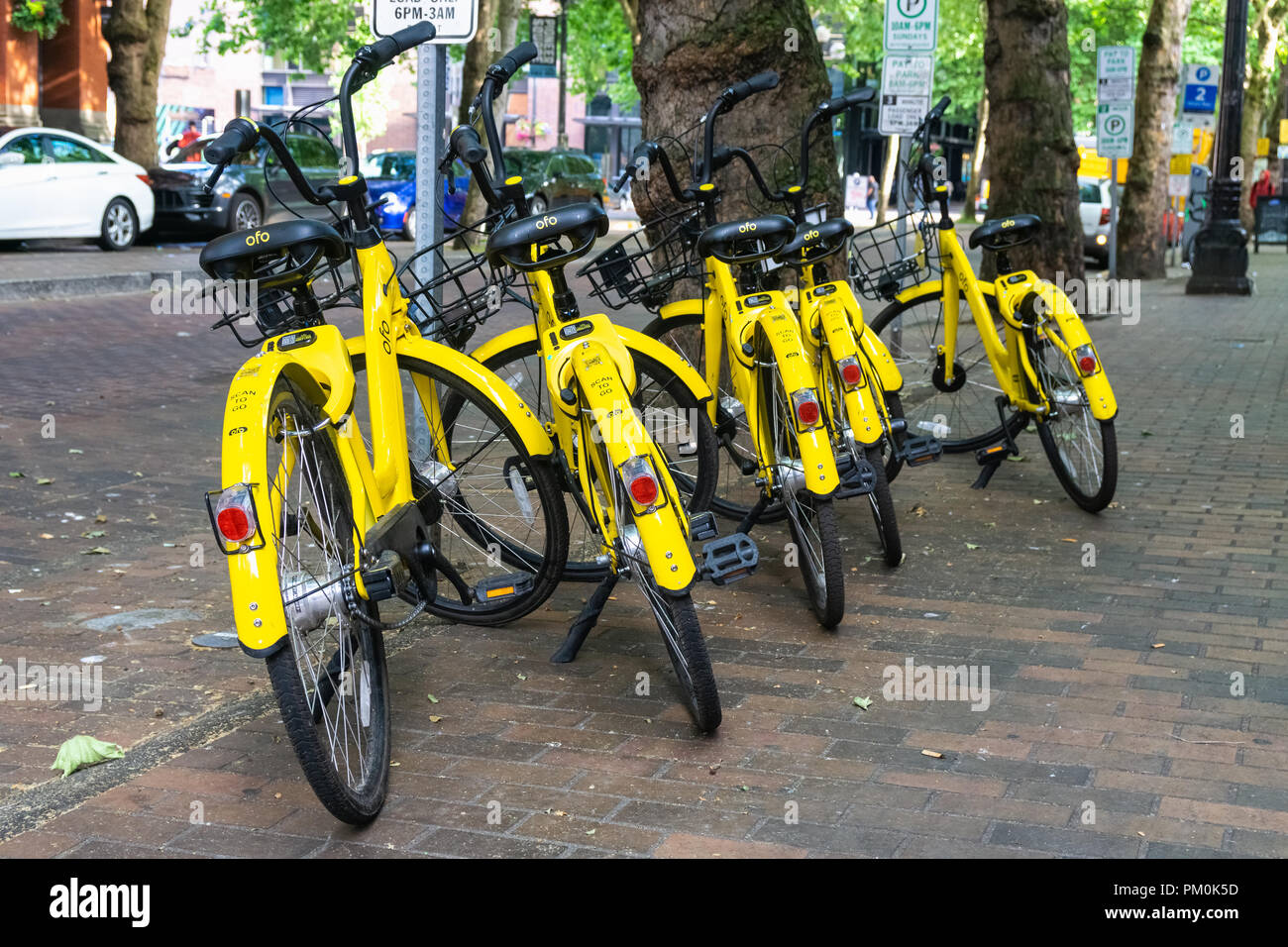 Groupe de partage de vélos Ofo jaune garée sur un trottoir dans le quartier de Pioneer Square dans le centre-ville de Seattle, USA. Ofo arrêter ses opérations en juillet 2018. Banque D'Images