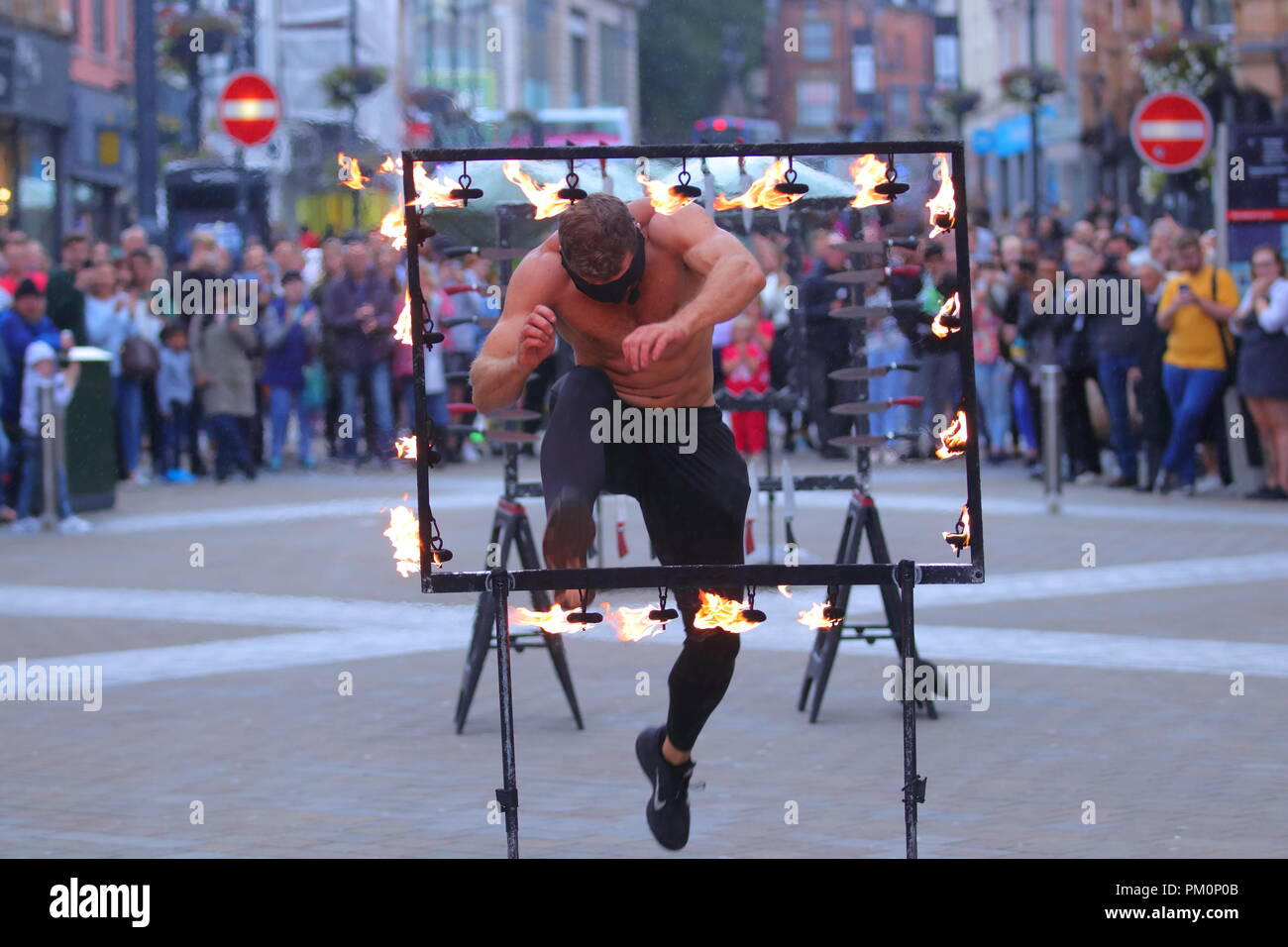 Un dare devil jette son soi par des couteaux & fire les yeux bandés dans le cadre de sa loi sur le théâtre de rue Briggate, Leeds, West Yorkshire. Banque D'Images