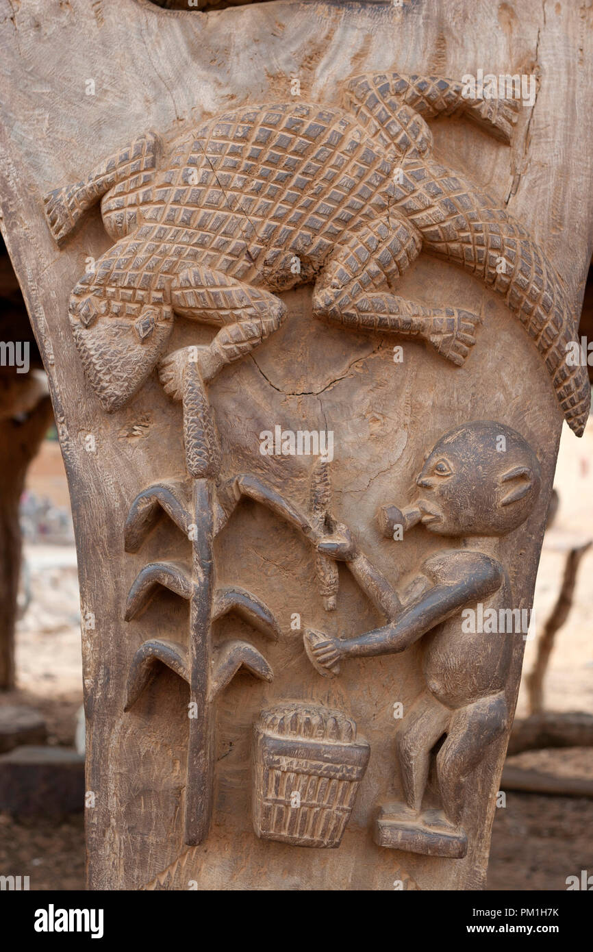 Sculpture en bois Dogon sur un "toguna" (ou cabane de palabre) pilier. La sculpture représente un crocodile et un homme millet de récolte Banque D'Images