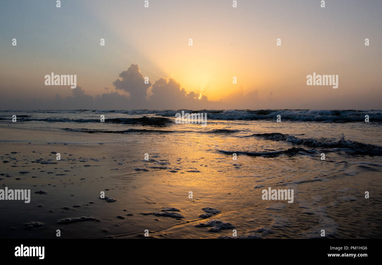 Le lever du soleil sur les nuages à l'horizon sur mer calme avec plage et des vagues Banque D'Images