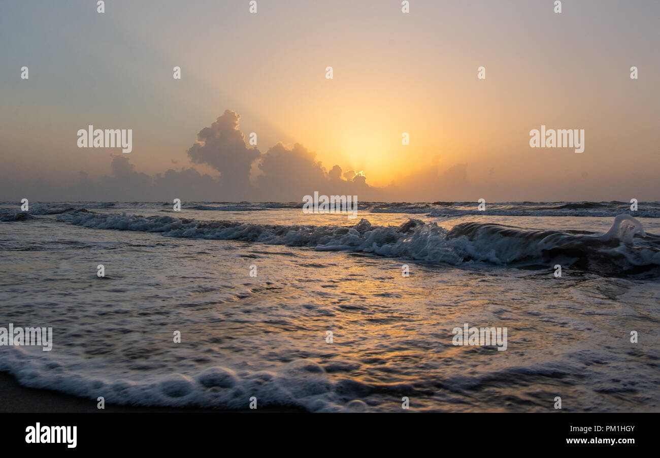 Le lever du soleil sur les nuages à l'horizon sur mer calme avec plage et des vagues Banque D'Images