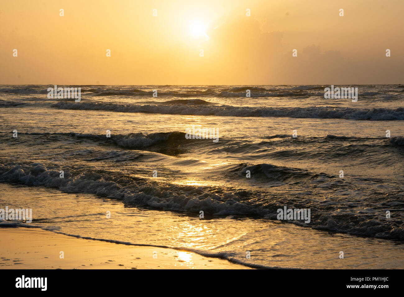 Le lever du soleil sur les nuages à l'horizon sur mer calme avec plage et des vagues Banque D'Images